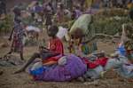 A young South Sudanese boy sits on a bundle of clothes at Dzaipi Recep...