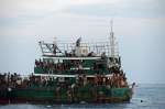 Refugees gather supplies airdropped to a fishing boat adrift in the An...