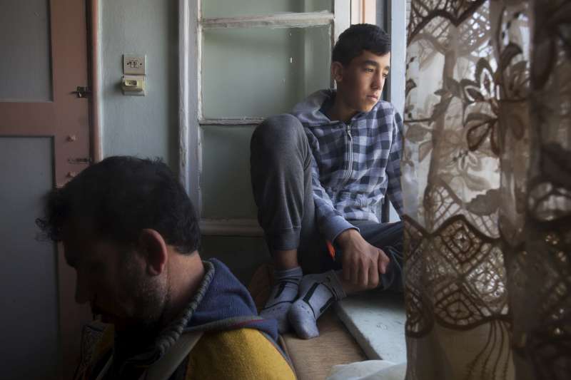Malak, 13, looks out of the window next to his father in the [&hellip;]