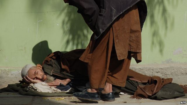 An elderly man lies on the ground as he begs in Kandahar. (file photo)