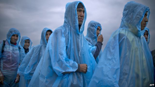 Migrants and refugees wearing raincoats queue at a camp to register after crossing the Greek-Macedonian border near Gevgelija, Macedonia.