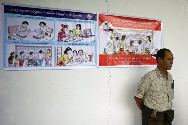A man stands beside election posters at the Zabuthiri district election commission office in Naypyidaw, Aug. 14, 2015.