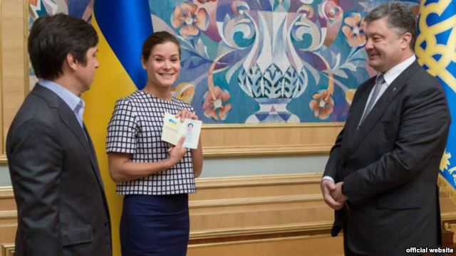 Maria Gaidar (center) holds aloft her newly issued Ukrainian passport, which was presented to her by President Petro Poroshenko (right). Journalist Vladimir Fedorin (left) was also granted Ukrainian citizensjip. 