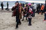 A family of refugees walk along the beach after landing on the Greek i...