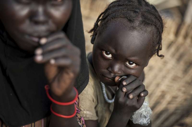 Displaced children in Maban county, South Sudan. Credit: Sebastian Rich / 2013
I have tattoos; far too many. But doubts over my decision to be inked extensively vanish in the world's refugee camps. Children from many cultures have never seen tattoos and the sight of this rather large photographer, sleeves rolled up, with a veritable cornucopia of butterflies, flowers, and dolphins, causes much intrigue and mirth in little eyes. For a few minutes while I am photographing and playing with the little ones they forget the horrors that brought them here, intrigued by the ink. The braver ones touch my arms and run away, then come back cautiously with huge smiles. Then it starts, all the children giggling at once, my interpreter bombarded with a hundred questions about my tattoos, as their smiles grow and grow.
Recently in a camp managed by the United Nations refugee agency in Maban County, South Sudan, a young girl of about seven years had been following me around as I photographed daily life. Every now and then a tiny warm hand would hold me gently by the wrist. I looked down to see her intently studying several butterflies. I asked my interpreter Mohammad what she was saying, to which he replied: "It is nothing Sebastian, just silly children's things." I persisted and eventually Mohammad, somewhat embarrassed, told me. "She is saying it is so dirty in the camp with all the dust that she would like to take the butterflies from your arms and put them in her pockets to keep the wings clean and soft!" I stopped in my tracks. I have seen so much horror in my time as a photographer and most of it, thankfully as a self-protection mechanism, has been filtered out, but this little girl's innocence caused my world for a few minutes to crumble around me.
http://stories.unhcr.org/sebastian-rich-photographer-p1790.html
