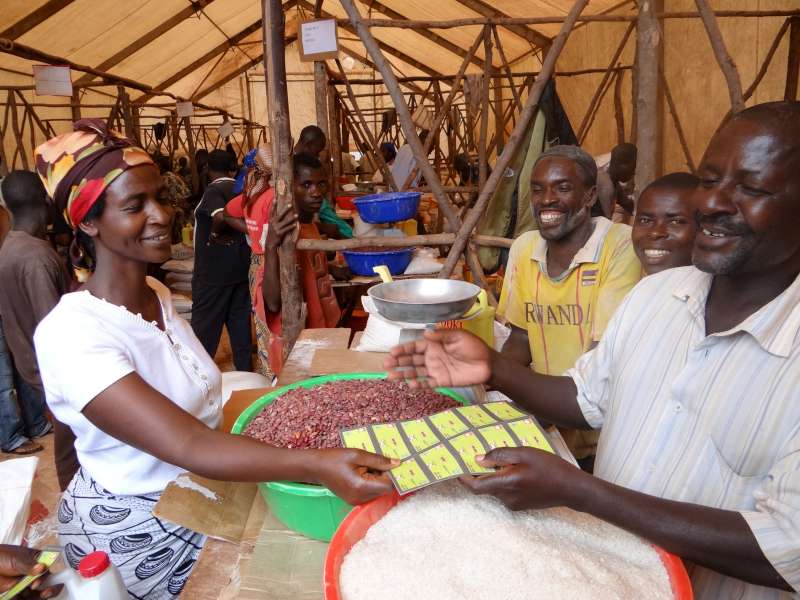 Congolese refugee Domitilla hands over vouchers to pay for beans. She'll cook them at home for her seven children.