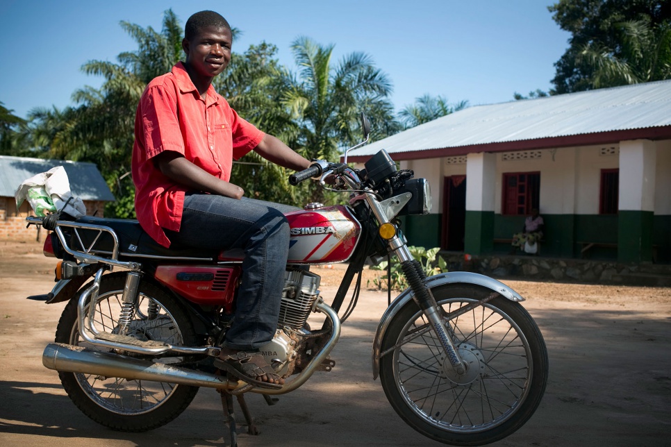Innocent sits on the motorbike he uses to transport passengers and goods to make a living.