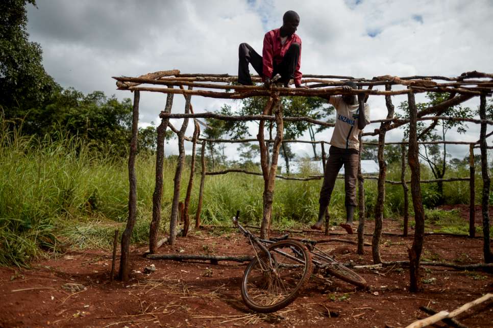 A young man builds a shelter with another refugee. Nduta refugee camp can barely provide enough shelter, household items, latrines and showers for its inhabitants.