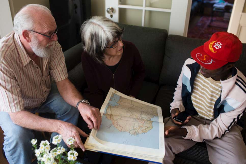 Judy Salomon and her husband look at an atlas with a gay Ugandan refugee they are hosting. 