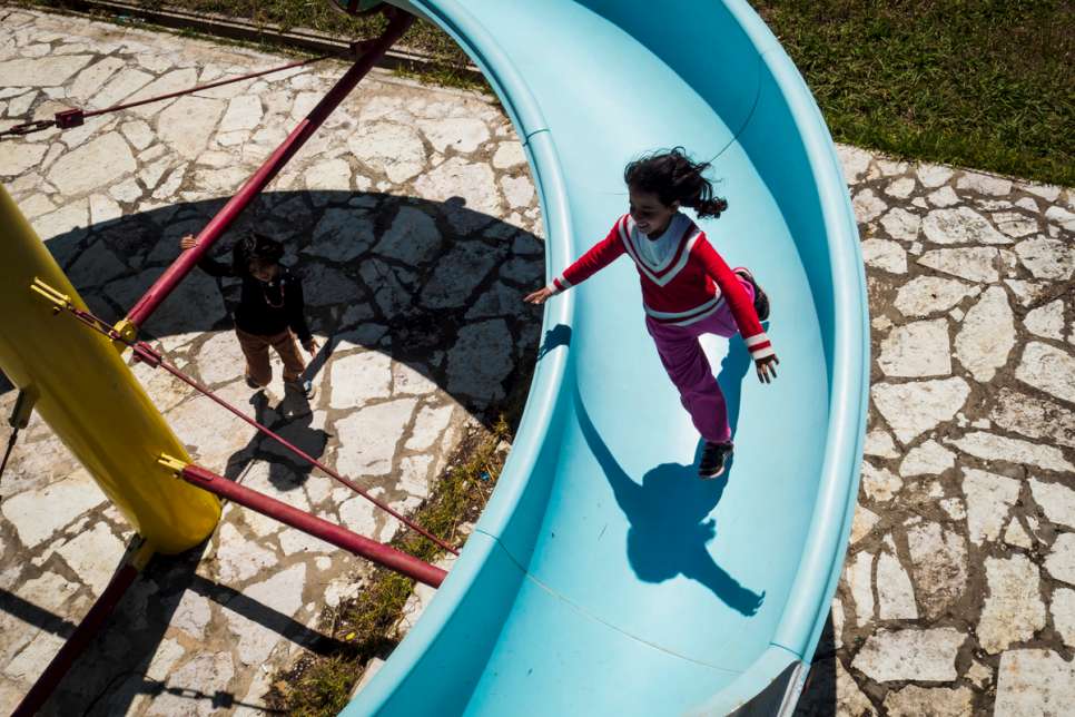 Syrian refugees Hala and Zeina play on a disused water slide inside LM Village.