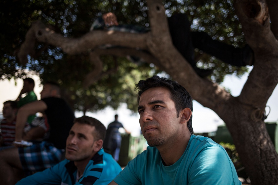 Ali and a friend sit outside the police station in Kos, Greece. They are waiting to register with the authorities and travel to Athens.