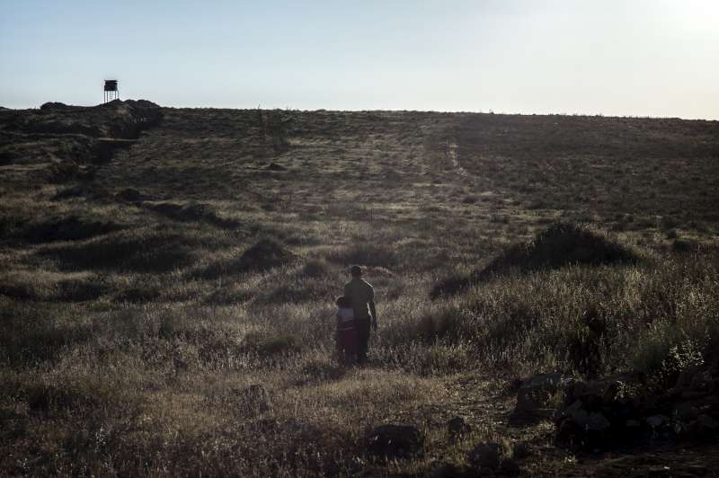 A Syrian man walks with his daughter along the border between Jordan and Syria. They had just crossed the border to escape the war.