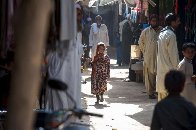 The bustling market place is the centre of the community in the Kot Chandana refugee village. Yet only men and younger girls wander freely.  Traditionally women are not allowed to shop there unless escorted by a male family member.  