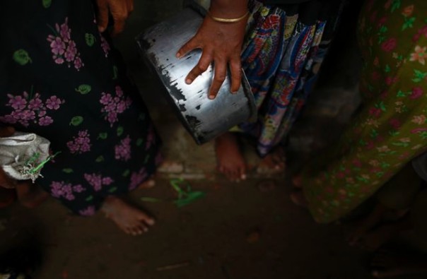 A Rohingya woman from a camp for internally displaced persons carries a pot as she lines up to collect food at a school outside of Sittwe, on May 17, 2013. REUTERS/Soe Zeya Tun