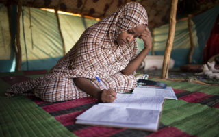 Tinalbarka, refugiada maliense de 16 años, estudia dentro de la tienda de campaña de su familia en el campamento de refugiados de Mbera, en Mauritania.