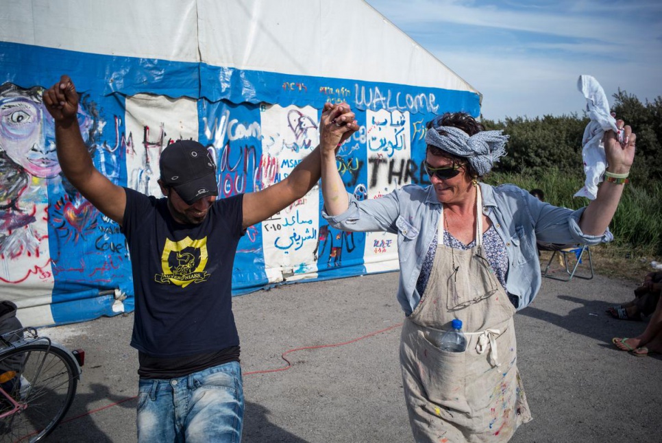 Nadine Mégard, 60, from Calais, dances with an Afghan refugee in the so-called "Jungle" near Calais.