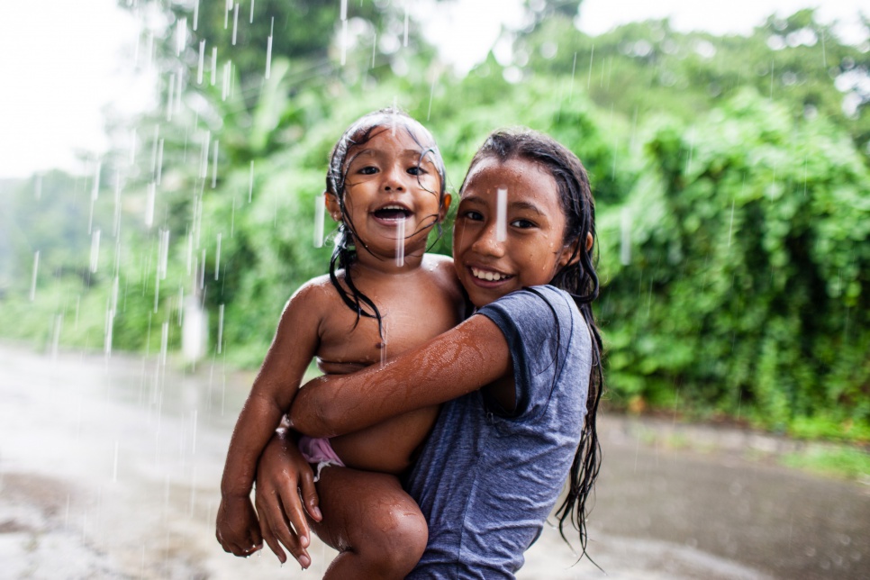 Ten-year-old Jessica and her sister Sara - not their real names - enjoy being children again, playing in the rain outside their house in Chiapas, Mexico. Their family escaped gang violence in El Salvador and hope to start over in Mexico, where they have been recognized as refugees.