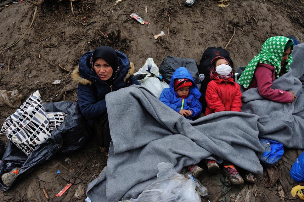 A mother and her children huddle under blankets in the mud at the Serbian border with Croatia. UNHCR distributes blankets and tents to help refugees keep warm, especially women, children and the elderly.