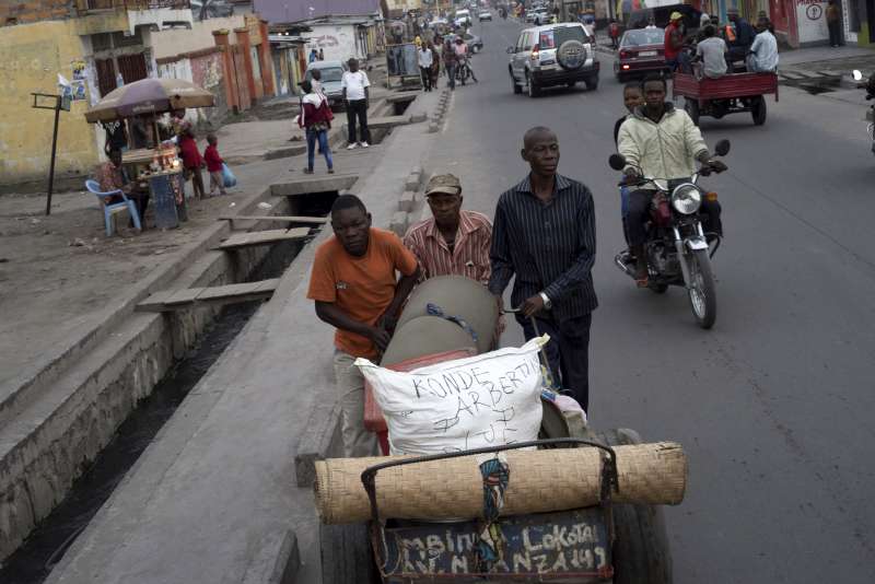 Antonio (in dark) pushes his luggage on a cart through the streets of Kinshasa en route to a pickup point, where UNHCR and its partners will collect it for transportation to Angola.