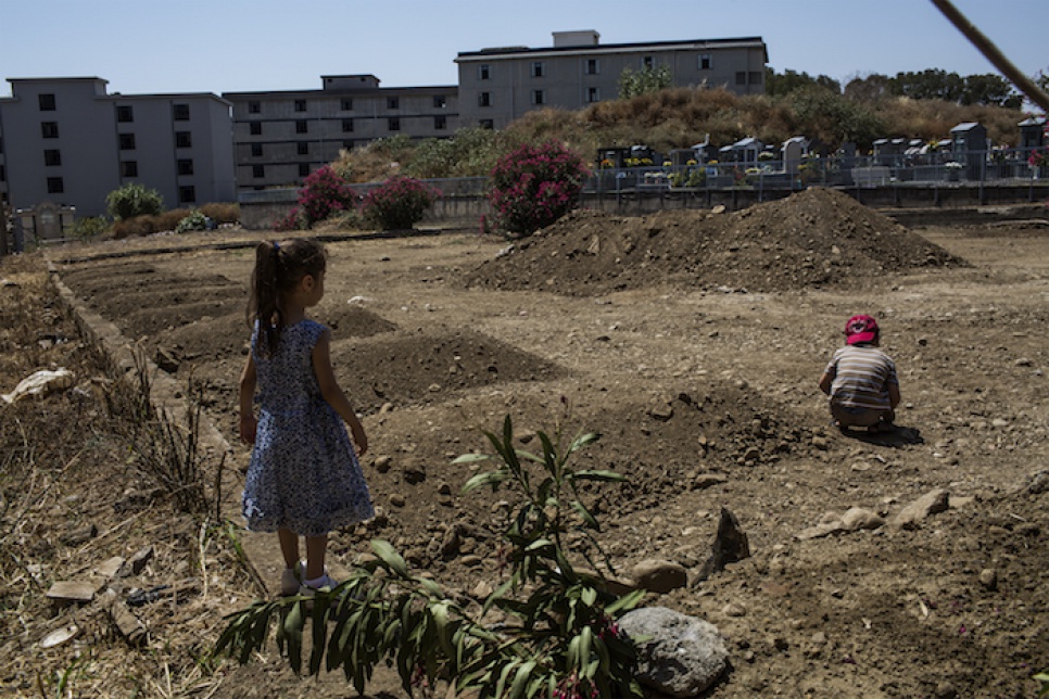 Three-year-old Liain plays with her brother near the grave of their grandmother at the municipal cemetery in Catania, Italy.