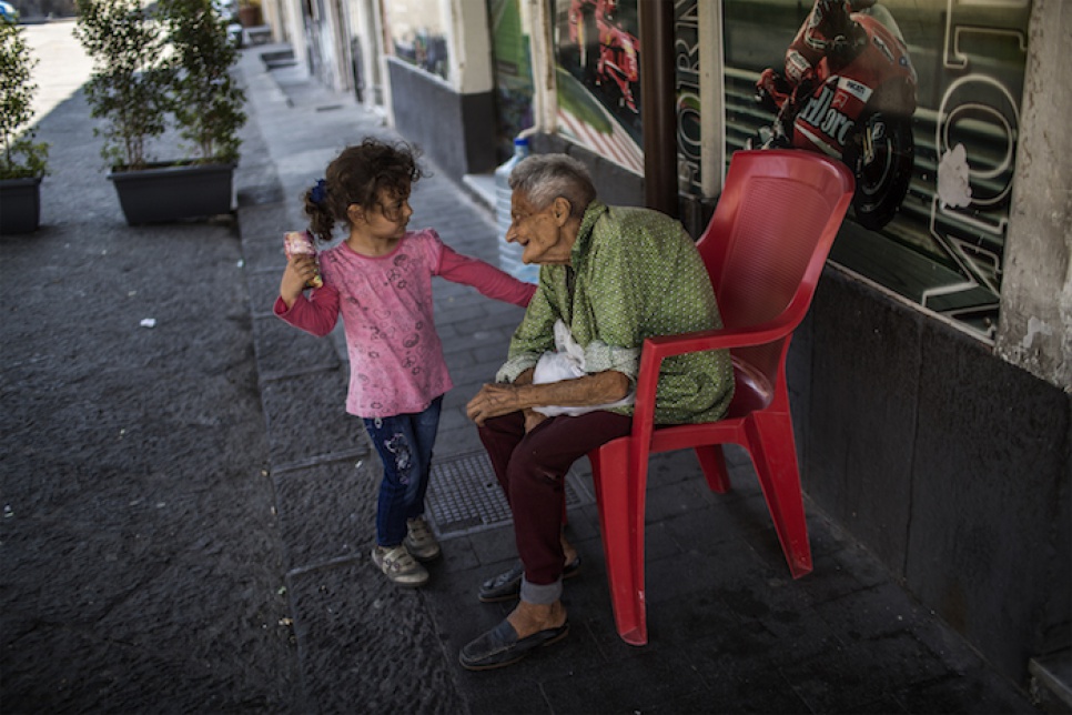 Three-year-old Liain from Syria plays with a Sicilian woman in front of a bar near the central mosque of Catania, Italy.