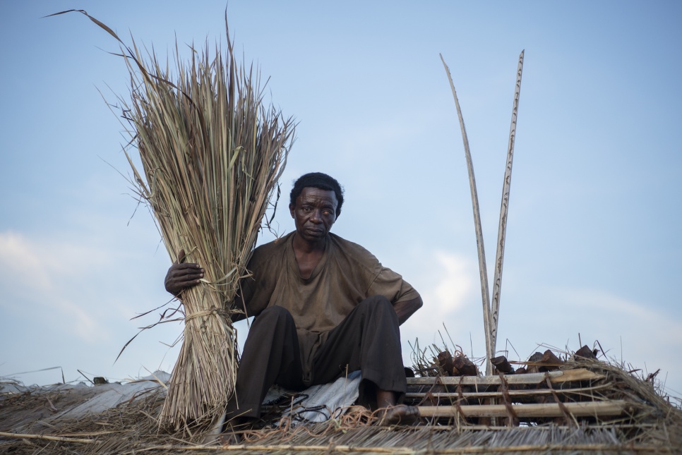 Step 4: Build a Permanent House. Prosper Singa, 52, works on thatching the roof of his newly erected home in Lukwangulo.