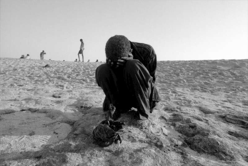 A côté des maigres possessions qu'il a réussies à sauver, un jeune homme s'effondre en larmes, après avoir recherché, toute la nuit, son frère porté disparu.