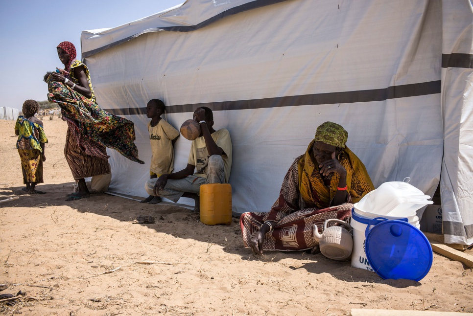 Kalthouma, Alhaji and other family members gather in the shade beside their new shelter in Dar-es-Salam settlement, near the village of Baga Sola, in the Lake Chad region in Chad.