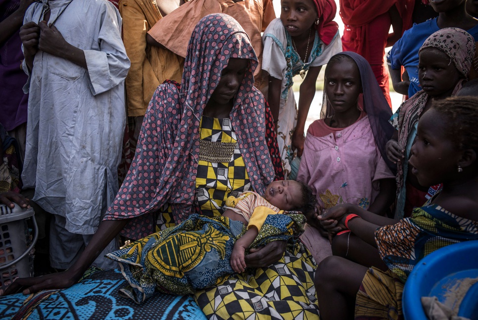 Kalthouma Abakar, 22, rests with her newborn daughter, Falmata Idris, after getting out of a canoe in Baga Sola, Chad. A truck will soon carry them to the Dar-es-Salam settlement.