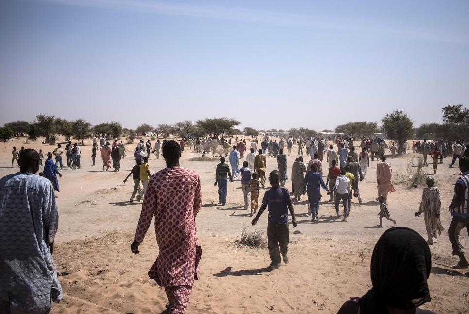 Nigerian refugees leave a food distribution site in Dar-es-Salam settlement, near Baga Sola, Chad. They are unfamiliar with sorghum, the grain provided by the World Food Programme.