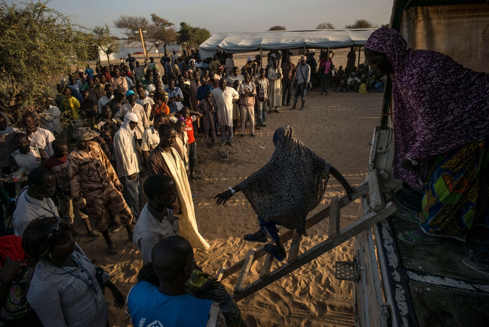 Nigerian refugees get off a UNHCR truck as they arrive in the Dar-es-Salam settlement near Baga Sola, Chad.
