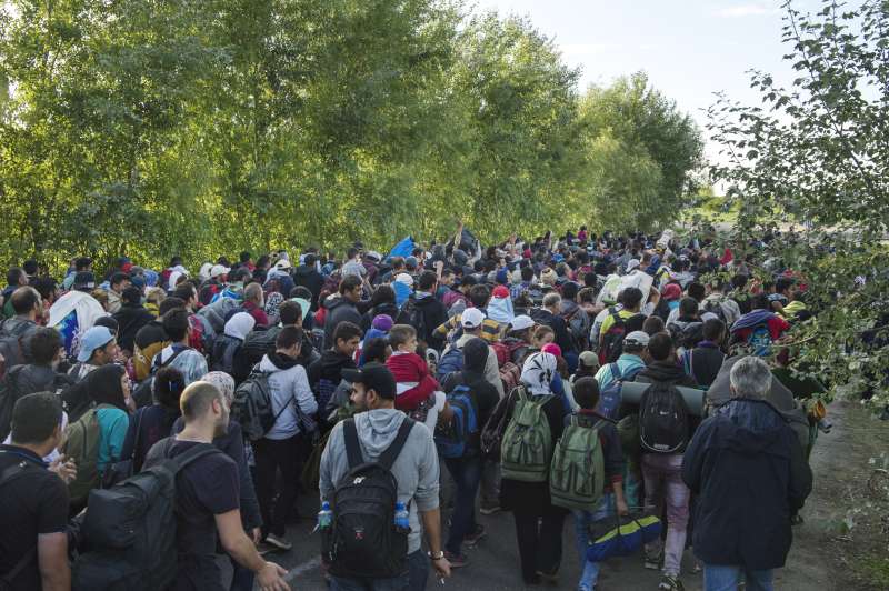 In Hungary, newly arrived refugees and migrants are accompanied by police on the road to the registration centre. Many had hoped to continue on from the border to Budapest and were chanting, "Budapest, Budapest..." 