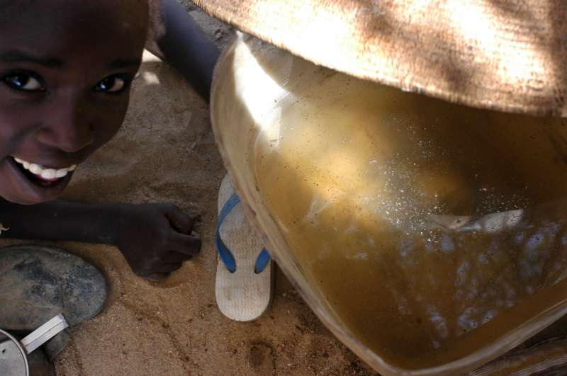 A refugee boy with untreated water collected from a local well in the border town of Bahai. UNHCR relocated refugees from the Bahai area to a camp at Oure Cassoni where safer, treated water is provided. (July 4, 2004)