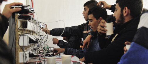 Crowds of young men around a station provided by UNHCR for charging mobile telephones at Vinojug Reception Center for refugees and migrants. The center is a kilometer along a dirt track from the Greek border. After registration, refugees and migrants must wait for trains to take them to the Serbian border, a wait that is often longer than the journey itself, which takes roughly three hours. Thousands pass through the center every day. ; More than 643,000 refugees and migrants arrived in Europe via the Mediterranean sea this year, including 502,500 in Greece only. Many of the refugees and migrants are desperate to move quickly onwards to Western Europe, fearing that borders ahead of them will close. As of Tuesday morning, there were more than 27,500 people on the Aegean Islands, either awaiting registration or onward transport to the mainland, and 5,000 new arrivals were recorded every day.