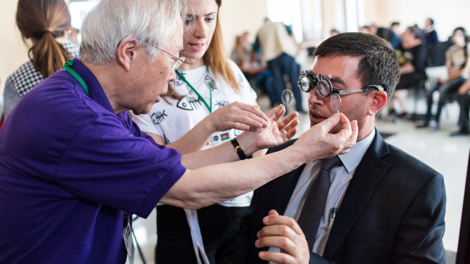 Optometrist Akio Kanai examines Yalchin Aghayev's eyes at a temporary clinic in Barda, Azerbaijan. Aghayev, who was displaced from his home by war two decades ago, was five years old when an accident left him with poor vision.