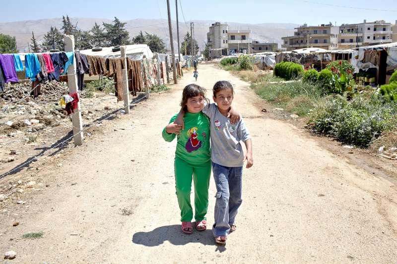  آية البالغة من العمر ثمانية أعوام (إلى اليمين)، تسير عائدة إلى المنزل على طول الطريق الترابي في قرية الدلهمية مع شقيقتها لبيبة. إنهما صديقتان حميمتان، وتعيشان في مخيم عشوائي للاجئين السوريين.
