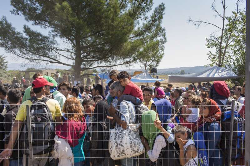 A young Afghan boy sits on his father's shoulders in the scorching mid-day sun on the border between Greece and fYR Macedonia. The group of refugees and migrants had been kept waiting for days by Greek police and were growing increasingly impatient to cross into fYR Macedonia.