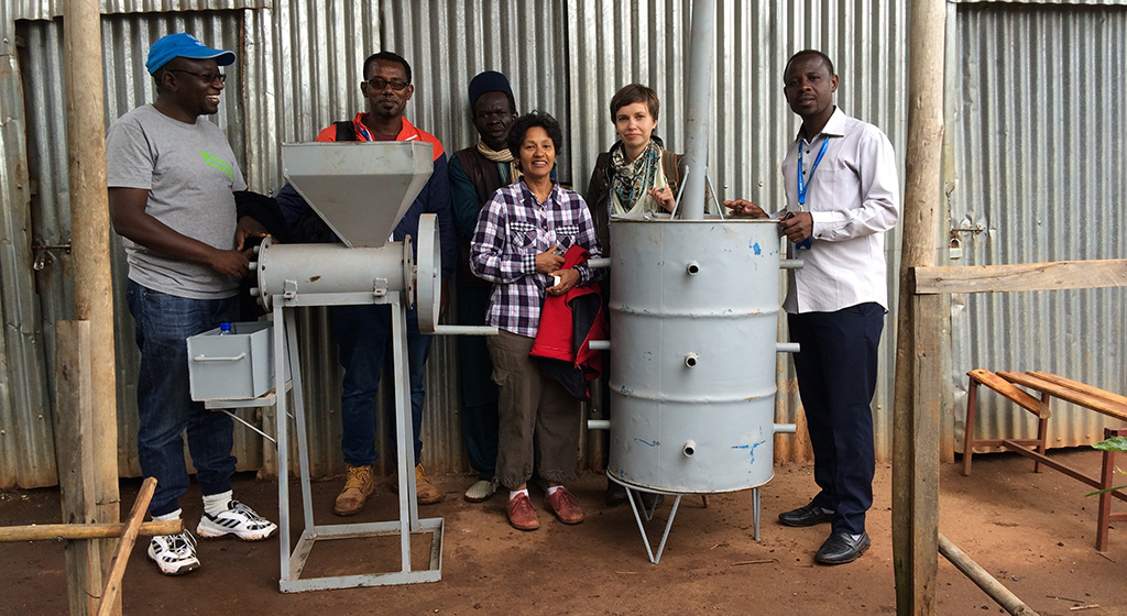 Simeneh (second from left) stands with a prototype of his briquette-making machine. 
