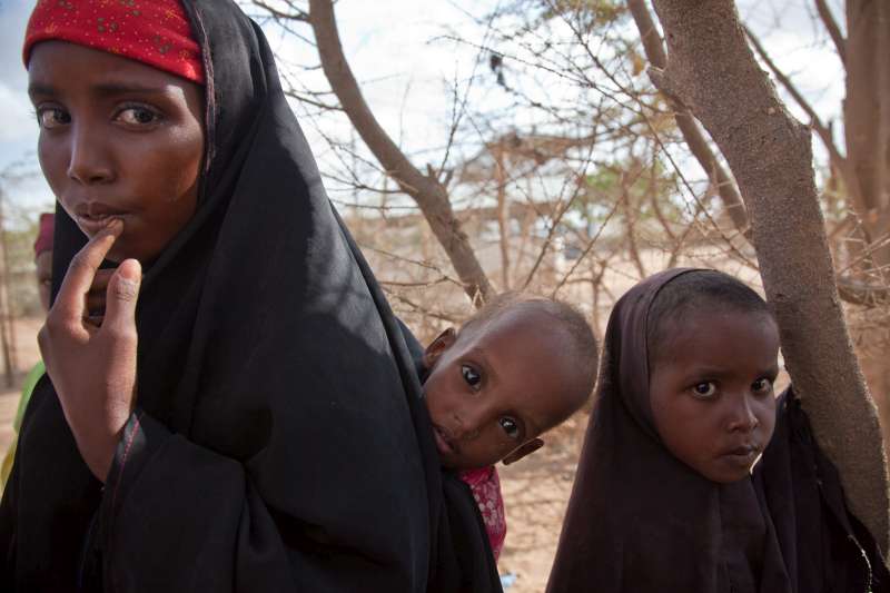 اللاجئة الصومالية داهيرا، 11 عاما، تحمل شقيقها الأصغر الذي يعاني من سوء التغذية الحاد على ظهرها في مخيم داغاهلي، أحد مخيمات مجمع داداب الواقع شمال شرق كينيا. لقد قطعت الأسرة طريقها إلى مخيم داداب؛ أكبر مجمع لمخيمات اللاجئين على مستوى العالم، هرباً من الجفاف والحرب في إقليم باي الصومالي. أُدخل مَاهد مستشفى المخيم في اليوم الذي التقطت فيه هذه الصورة.