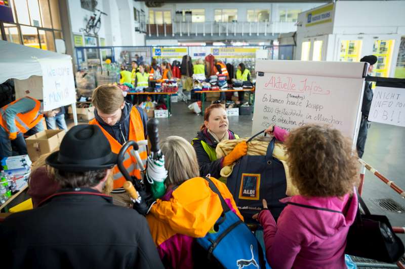 Des bénévoles munichois distribuent des sacs remplis de produits utiles aux réfugiés et aux migrants qui arrivent à la gare ferroviaire. 
