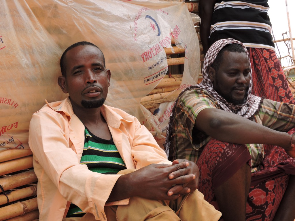 Two refugees sit against a wall in the Dollo Ado refugee camp. 