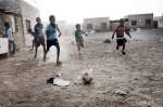 أطفال يلعبون كرة القدم على أرض موحلة في مخيم خرز للاجئين.