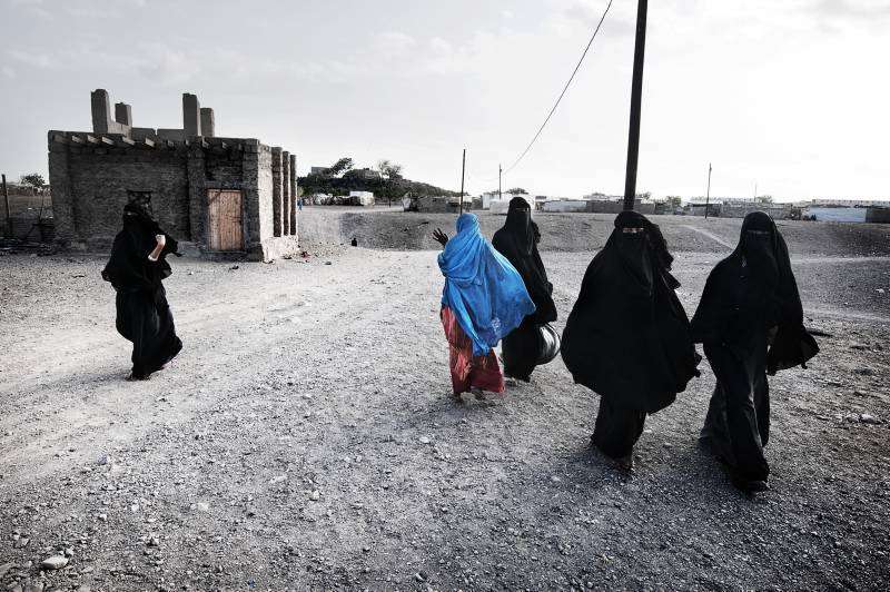 مجموعة من النساء تسير في مخيم خرز للاجئين. ترتدي معظم النساء في اليمن "العباية" إلى جانب النقاب.