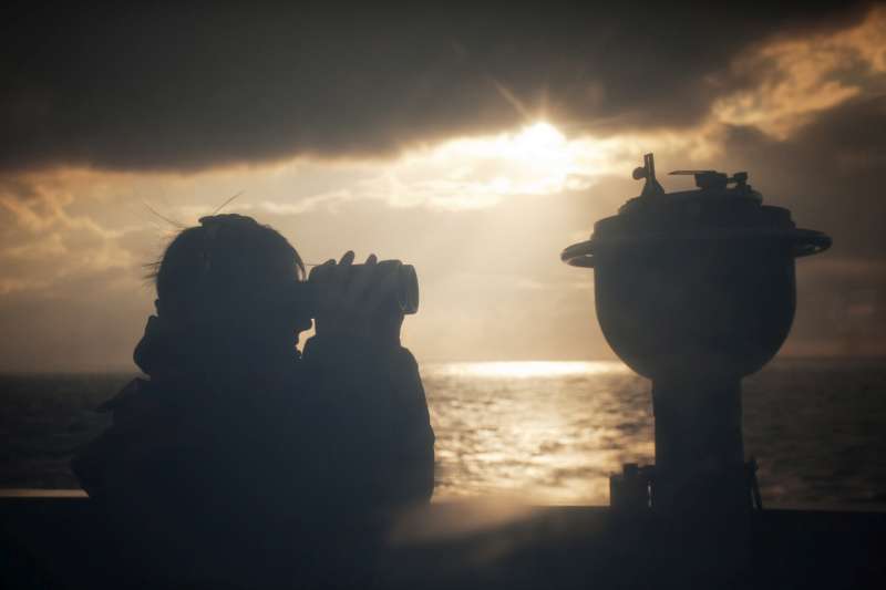 بحار على جسر سان جوستو يستطلع بمنظاره المكبر على مرمى البصر بحثاً عن القوارب التي تحمل أشخاصاً من ليبيا. تجرى عمليات المراقبة على مدار الساعة من على متن السفينة. 