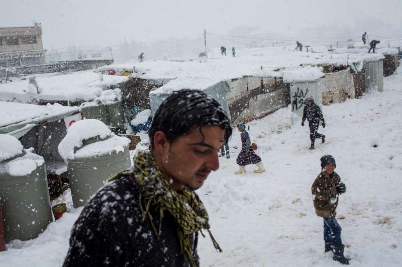 لاجئون سوريون يتنقلون بين المآوي في مخيم عشوائي في مدينة زحلة في سهل البقاع. يضم البقاع أكثر من 850 مخيماً من هذا النوع، ويقيم في هذه المخيمات ما يزيد عن 144,000 شخص؛ إلا أن مآويهم الواهية بالكاد تصمد في وجه الرياح والثلوج.