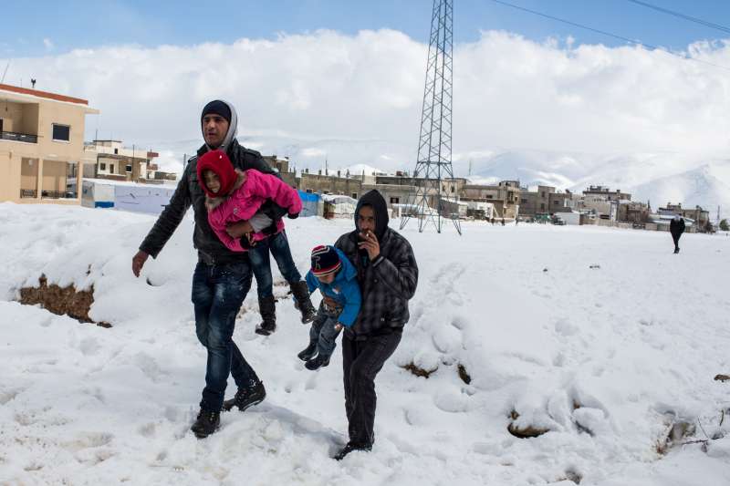 أبوان يحملان أولادهما ويعبران فوق الثلج في سهل البقاع اللبناني. يُتوقع أن تنحسر العاصفة الثلجية، إلا أن درجات الحرارة ستستمر في الانخفاض في الأيام المقبلة.