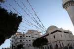 حبال مزدانة بعلم ليبيا الجديد ترفرف من أحد المساجد في طرابلس بعد عام من ثورة الشعب ضد النظام السابق. ولكن العديد من النازحين الداخليين لم يحتفلوا.