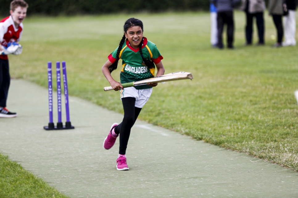 Vêtue du maillot de cricket du Bangladesh, une jeune fille court devant la ligne dans l'espoir de marquer un point pour le club de cricket de Carlow. 