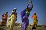 لاجئات من دارفور بالسودان يرتدين ملابس ملونة ويجمعن الحطب ويقطعنه في إحدى نقاط التوزيع الكائنة في مخيم تريغوين شرق تشاد. 