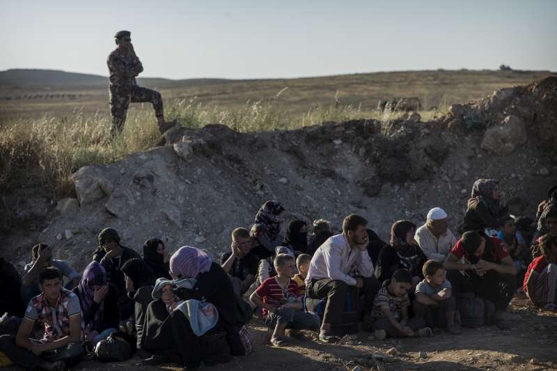 Syrians are instructed to wait behind a slope created by the Jordanian army to protect new arrivals.